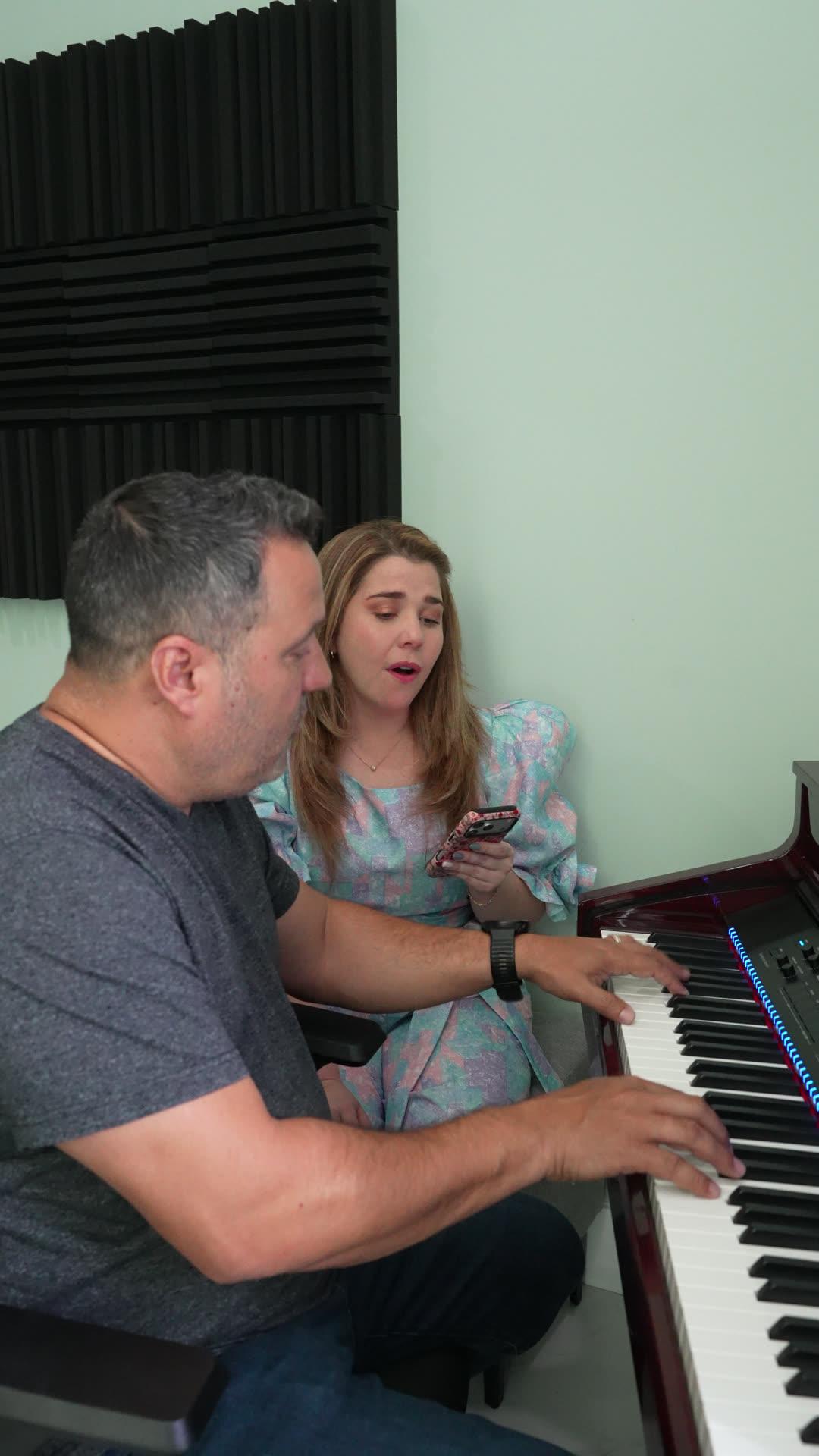 Producer at the piano working out an arrangement with a vocalist